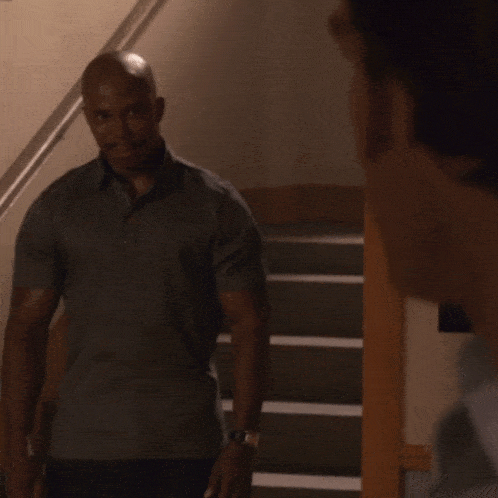 a bald man with a mustache is standing next to a metal railing
