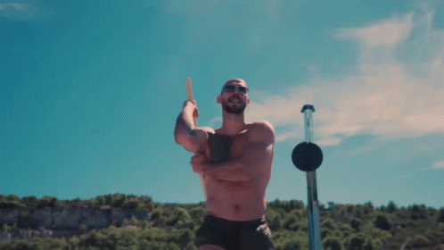 a man without a shirt is holding a stick in front of a blue sky