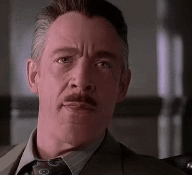 a man with a mustache is wearing a suit and tie and making a funny face .