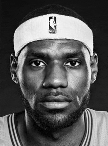 a black and white photo of a basketball player wearing a headband and a beard .
