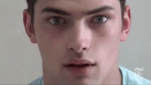 a close up of a young man 's face with his mouth open and his eyes looking at the camera .