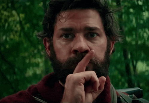 a man with a beard is holding his finger to his lips