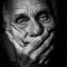 an old man is covering his mouth with his hand in a black and white photo .