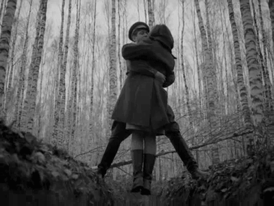 This may contain: black and white photograph of two people hugging in the woods