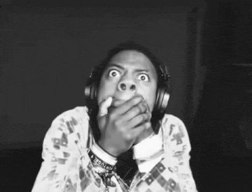 a black and white photo of a person wearing headphones and covering their mouth .
