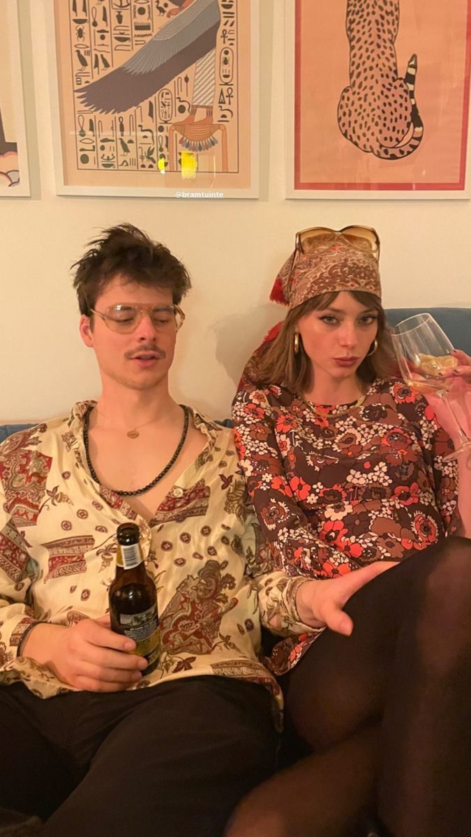 This may contain: a man and woman sitting on a couch next to each other with beer bottles in their hands