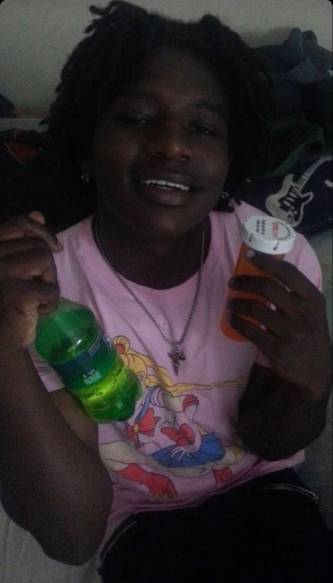 This may contain: a woman sitting on a couch with a bottle and toothbrush in her hand while smiling
