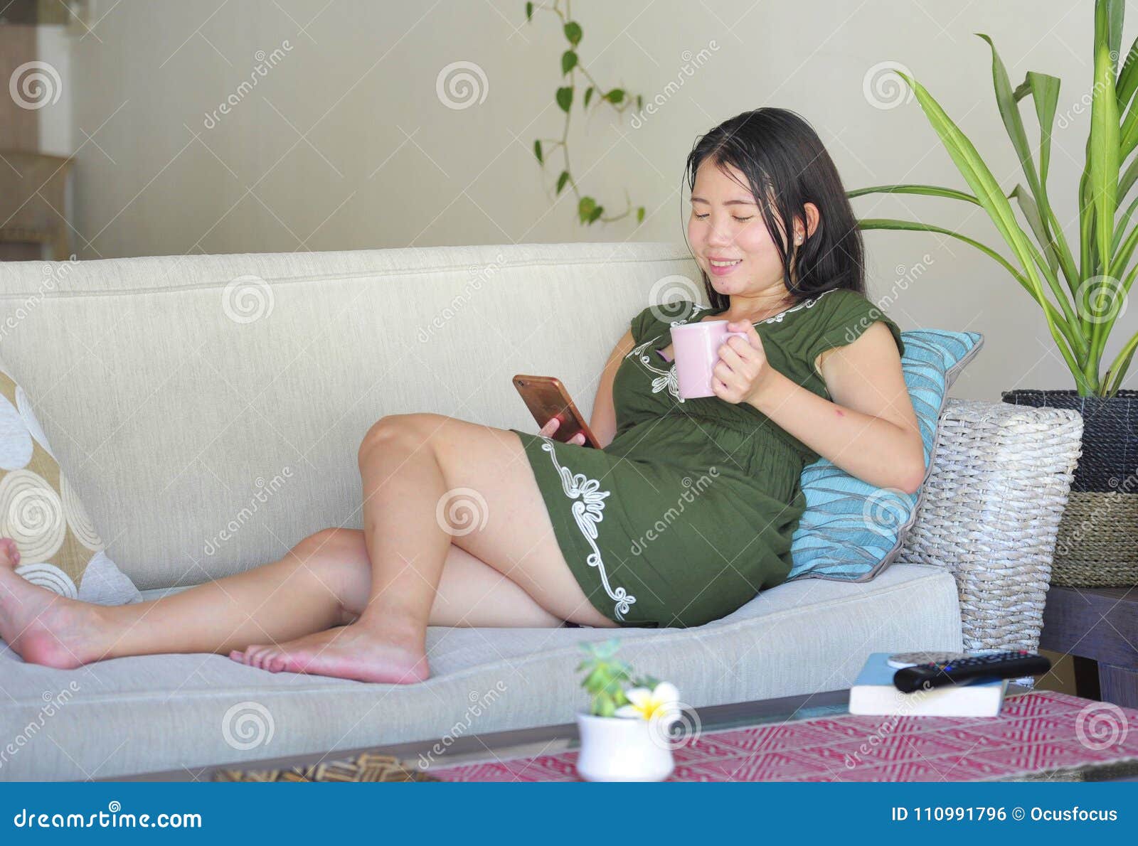 young-beautiful-relaxed-asian-chinese-woman-lying-home-living-room-sofa-couch-using-internet-mobile-phone-happy-110991796.jpg