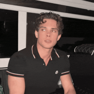 a young man wearing a black polo shirt with a moncler logo on it