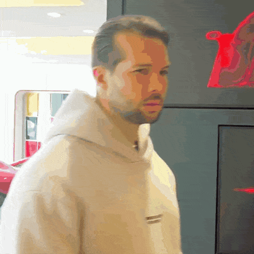 a man with a beard is wearing a tan hoodie with the word t on it