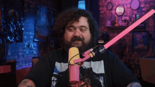 a man with a beard is sitting in front of a pink microphone with the word blue on it