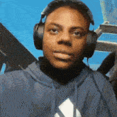 a man wearing headphones and a blue hoodie with an adidas logo