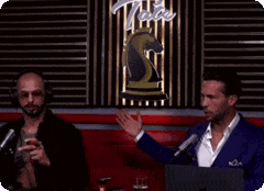 two men are talking to each other in front of a sign that says tate