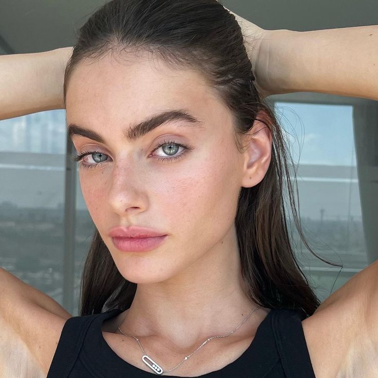 This may contain: a woman with long hair and blue eyes wearing a black tank top is posing for the camera