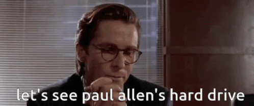 a man in a suit and glasses says  let 's see paul allen 's hard drive 