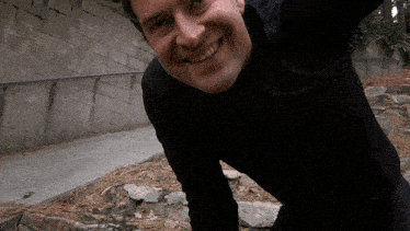 a man wearing a black shirt is smiling and looking at the camera