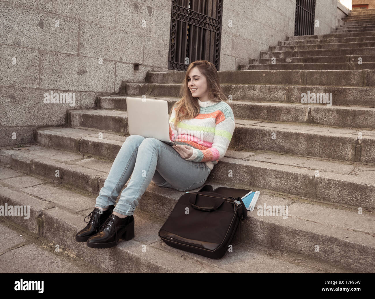 attractive-trendy-teen-student-girl-or-young-college-woman-working-on-laptop-on-the-internet-blogging-chatting-or-on-steps-in-urban-background-in-on-T7P96W.jpg