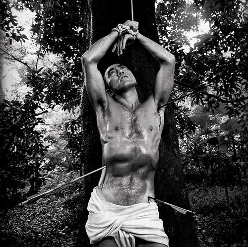 This may contain: a man with no shirt on is holding an object above his head while standing in front of a tree