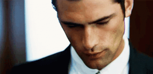 a man in a suit and tie looks down at something