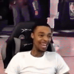 a man in a white shirt is smiling while sitting in a gaming chair .