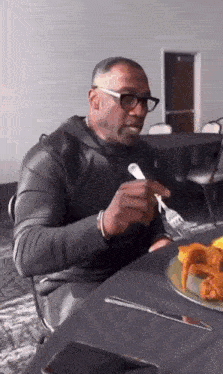 a man is sitting at a table eating chicken wings with a fork and knife .