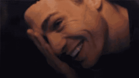 a close up of a man covering his face with his hand while laughing .