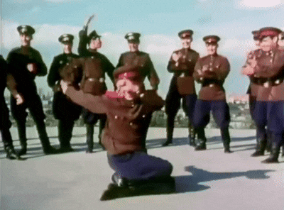 a group of men in military uniforms are standing around a man on his knees