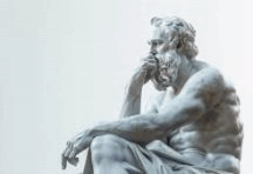a statue of a man with a beard and mustache is sitting down with his hand on his chin .