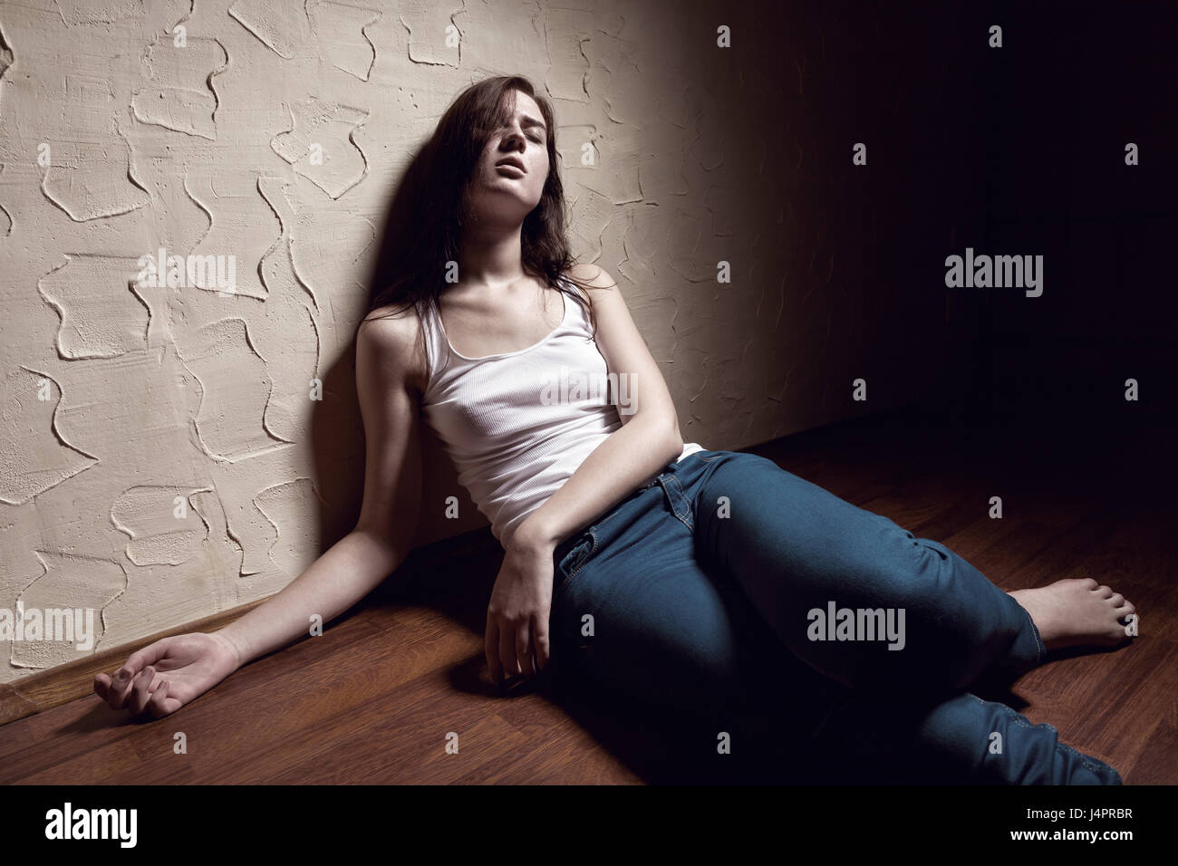 girl-addict-unconscious-sitting-on-the-floor-J4PRBR.jpg