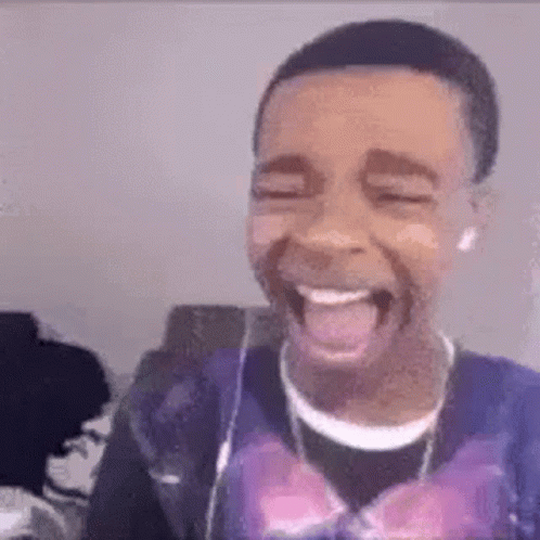 a young man is laughing with his tongue out while wearing headphones and a purple shirt .