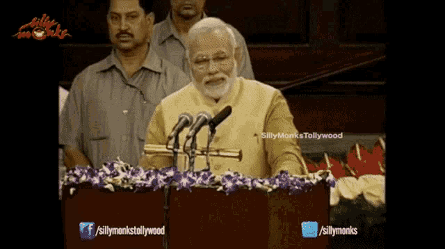 a man is giving a speech in front of microphones with the words silly monks on the bottom