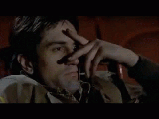 a man is sitting in a chair holding his hand to his face .