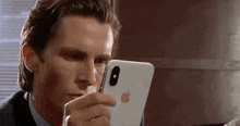 a man in a suit and tie is looking at his iphone .