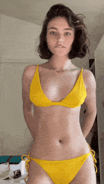 a young woman in a yellow bikini is standing in a room
