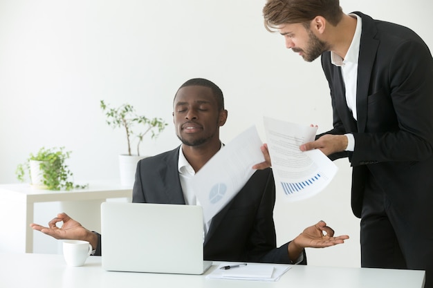 calm-african-american-businessman-practicing-yoga-work-ignoring-angry-boss_1163-3911.jpg