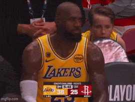 a man wearing a lakers jersey watches a game