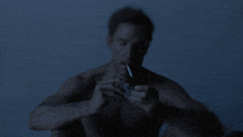 a shirtless man lighting a cigarette with a lighter