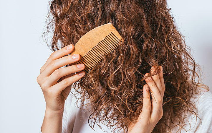 Woman combing her curly hair