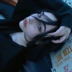 This may contain: a woman with black hair and piercings is laying on the floor wearing a hoodie
