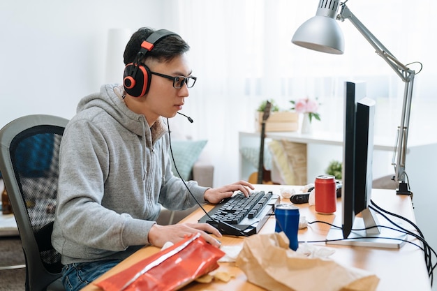 technology-gaming-entertainment-concept-happy-young-asian-man-headphones-with-pc-computer-playing-game-streaming-playthrough-video-lazy-college-boy-relax-home-summer-break-eat-junk-food_678158-1866.jpg