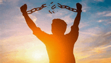 a silhouette of a man holding chains in his hands at sunset . a silhouette of a man holding chains in his hands at sunset .