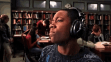 a man wearing headphones in a library with the city tv logo visible a man wearing headphones in a library with the city tv logo visible