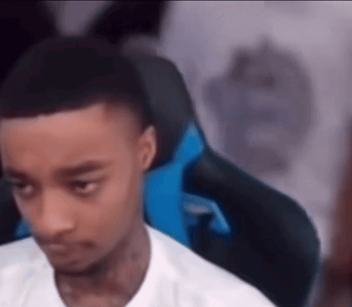 a young man is sitting in a gaming chair looking at the camera . a young man is sitting in a gaming chair looking at the camera .