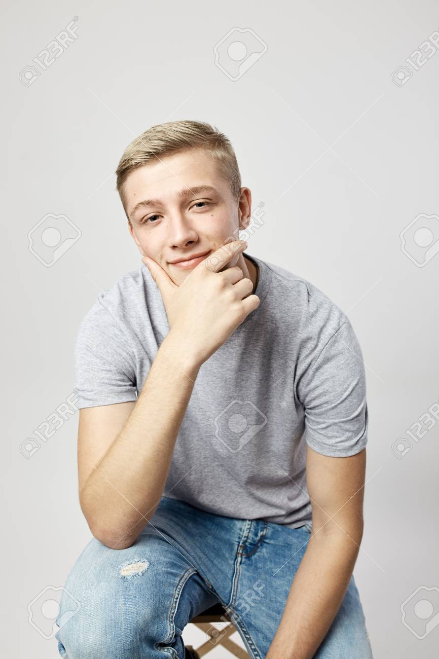 117515094-blond-guy-dressed-in-a-white-t-shirt-stands-on-the-white-background-in-the-studio-holding-his-hand-o.jpg