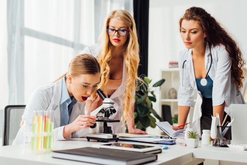 selective-focus-sexy-nurse-looking-microscope-near-women-175872218.jpg